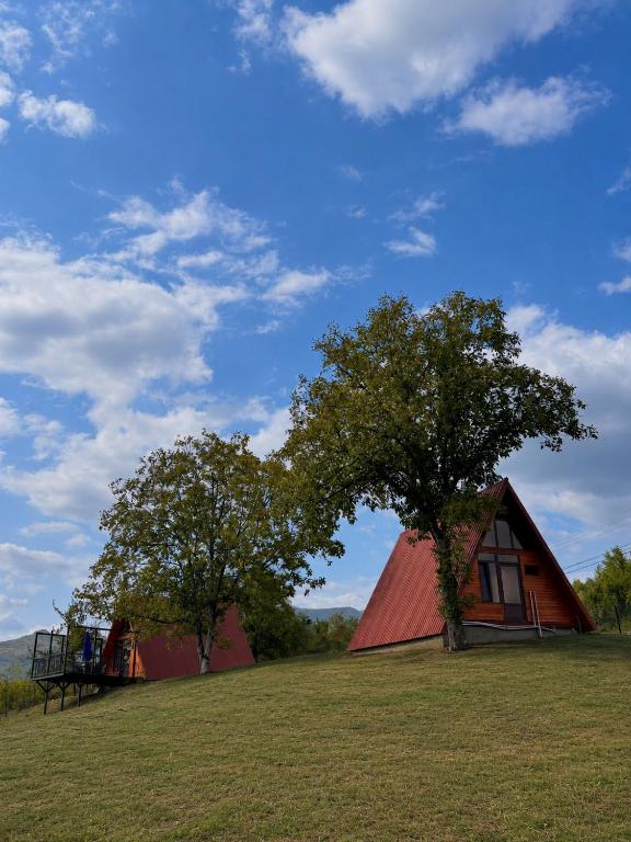 a red barn with a tree in a field at Helios racha in Ambrolauri