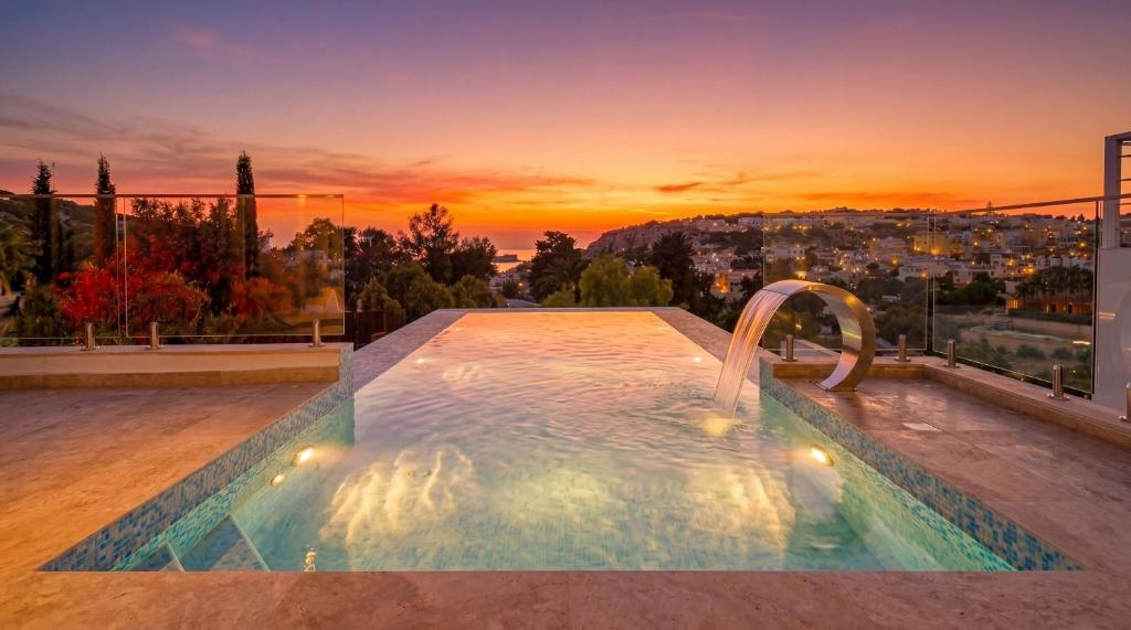 a swimming pool on top of a building with a sunset at Maltese Luxury Villas - Sunset Infinity Pools, Indoor Heated Pools and More! in Mellieħa