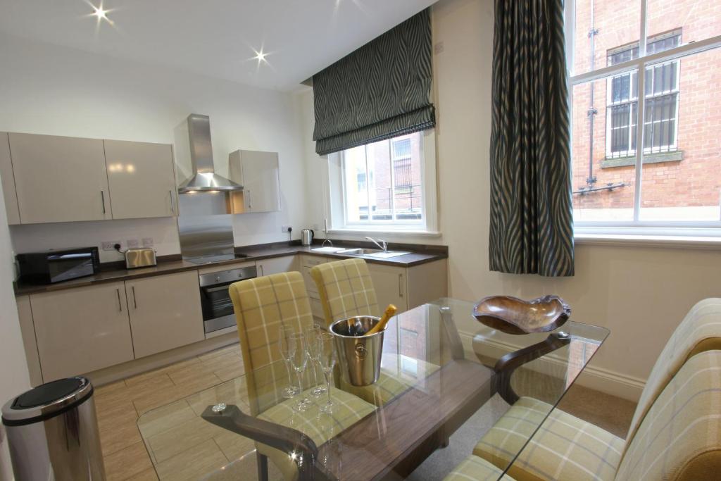 a kitchen with a glass table and yellow chairs at The Castle Collection - 25 Castle Street in Liverpool