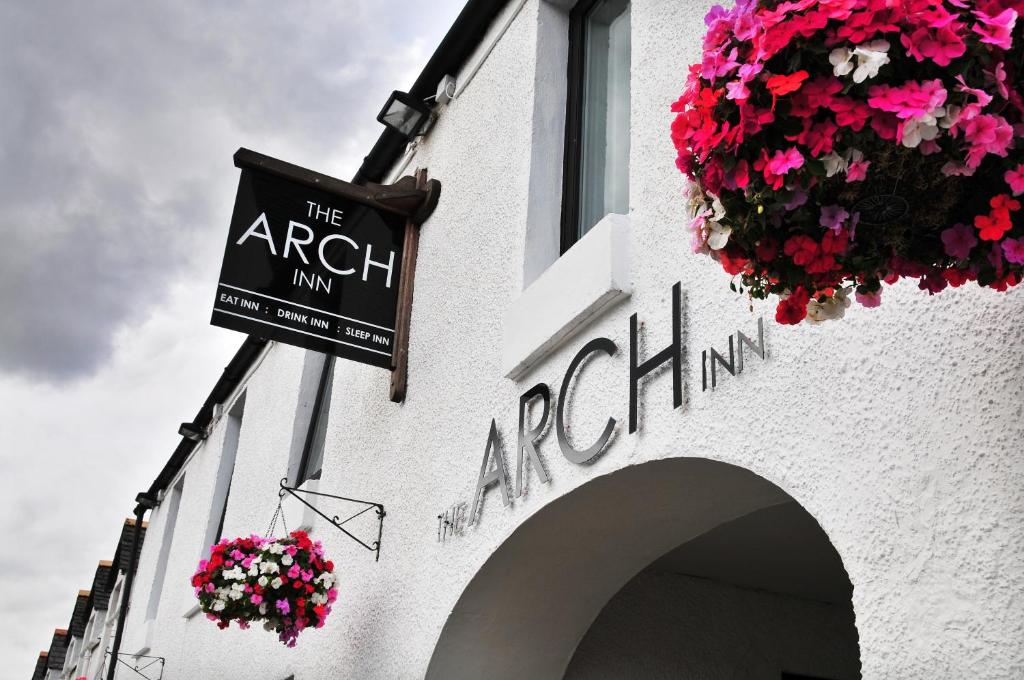 una señal en el lado de un edificio con flores en The Arch Inn, en Ullapool