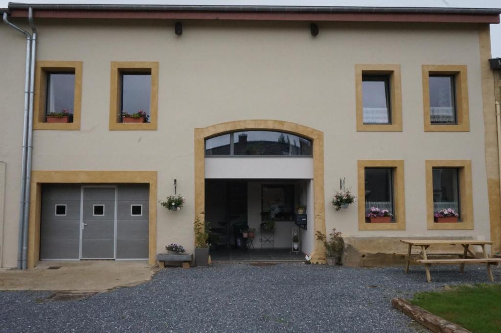 a house with two garage doors and a bench at Gîte Le Fenil in Allondrelle-la-Malmaison