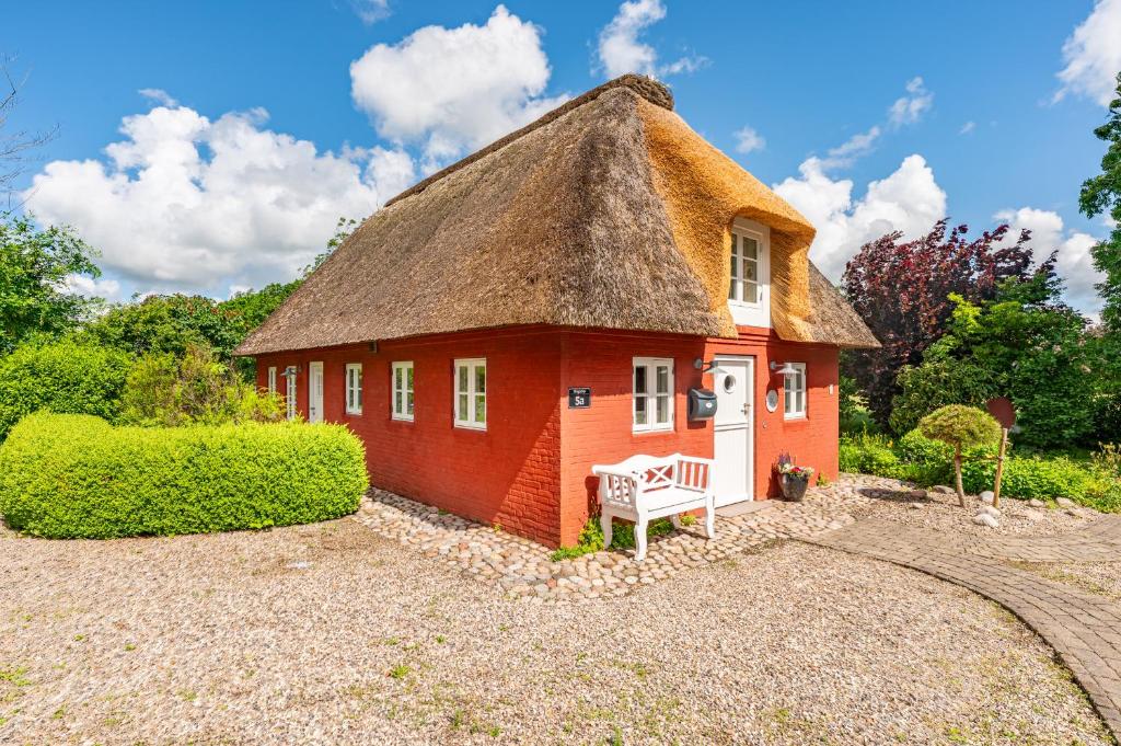 a small red house with a thatched roof at Ferienhaus Hyggehüs in Risum-Lindholm