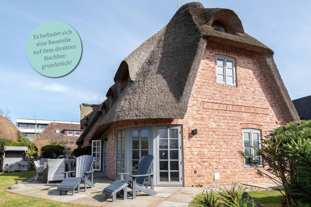 a house with a thatched roof with chairs outside at Haus Riva in Wenningstedt
