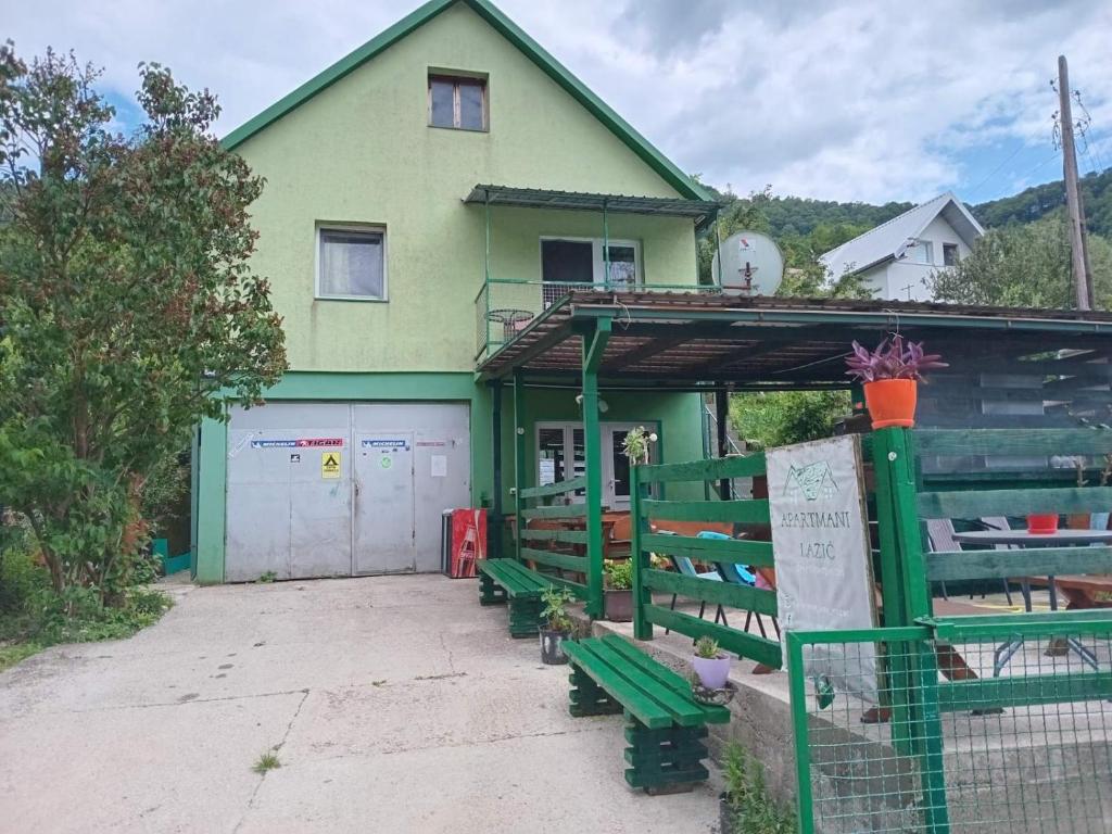 a green building with two green benches in front of it at Apartmani Lazić in Plužine