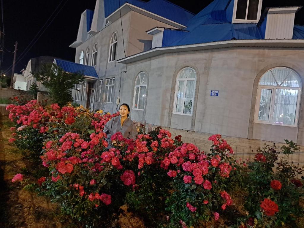 a woman standing in front of a bunch of flowers at GuestHouse "ERKIN" in Karakol