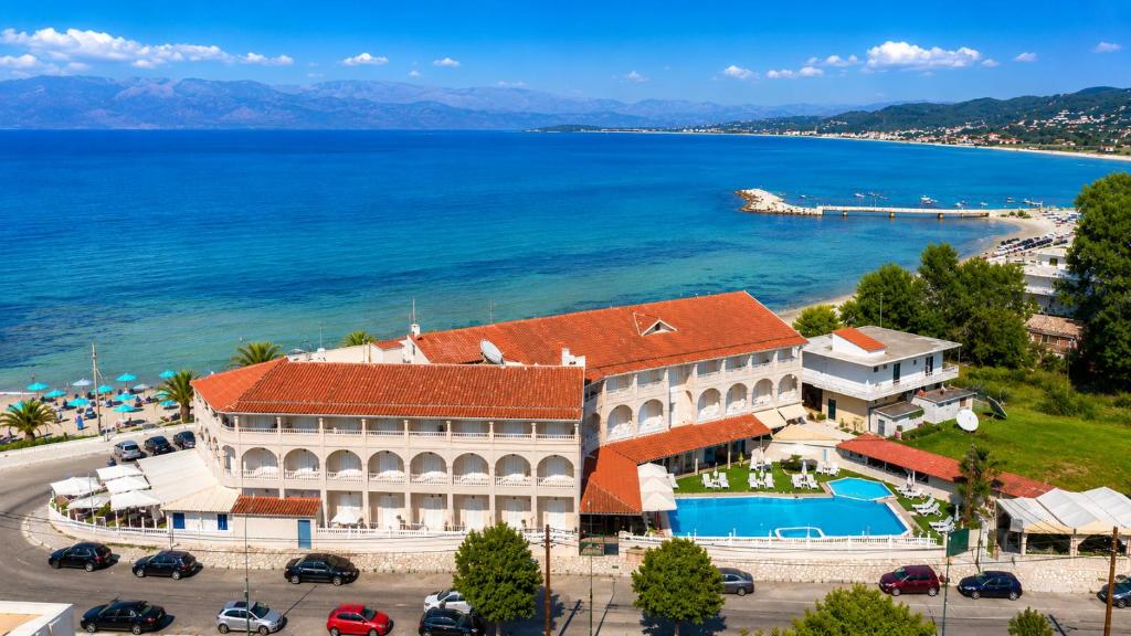 a building with a red roof next to a body of water at Aphrodite Beach Hotel Corfu in Roda