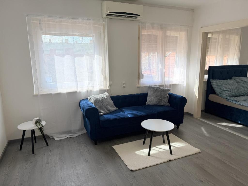 a living room with a blue couch and two tables at Beni Apartman in Szeged