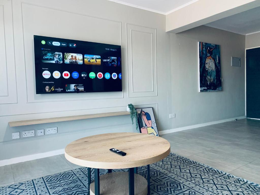 a room with a table and a tv on the wall at The Penguin Nest in Gaborone