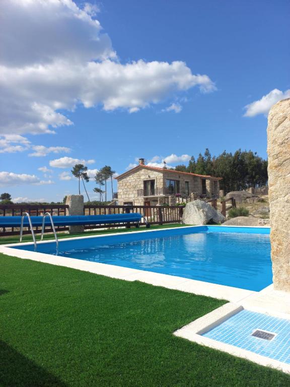 a swimming pool with green grass next to a house at Quinta Do Marmeiral in Mangualde