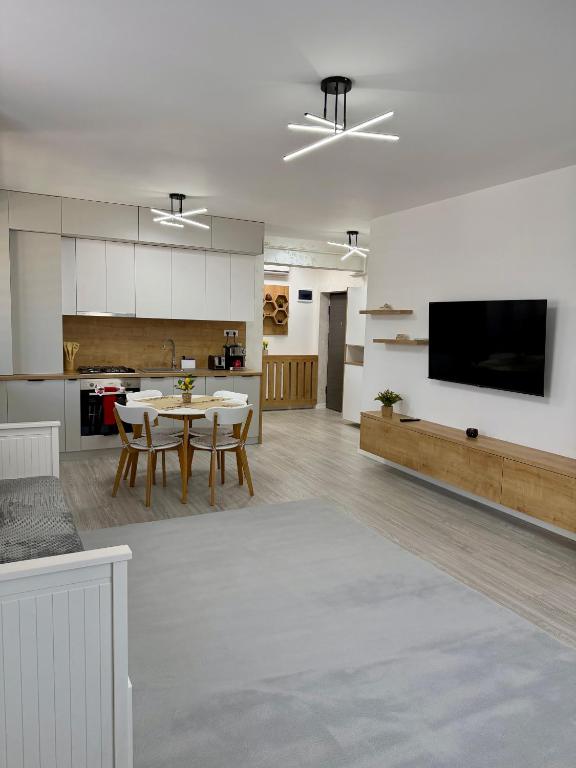 a kitchen and living room with a table and a tv at ND Central Apartment in Râmnicu Vâlcea