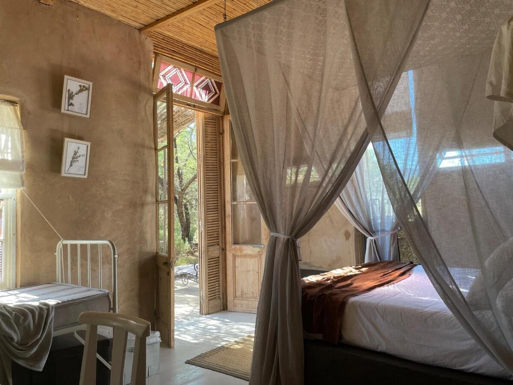 a bedroom with a canopy bed and a window at Strooi Kooi - Unique Strawbale Cottage in Calitzdorp