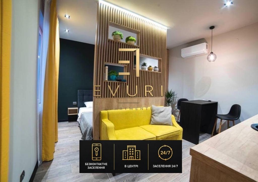 a yellow couch in a room with a bedroom at EVURI Apartments Petofi in Uzhhorod