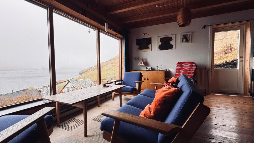 a living room with a blue couch and a table at Idyllic Vacation Home with a Breathtaking View in Bøur