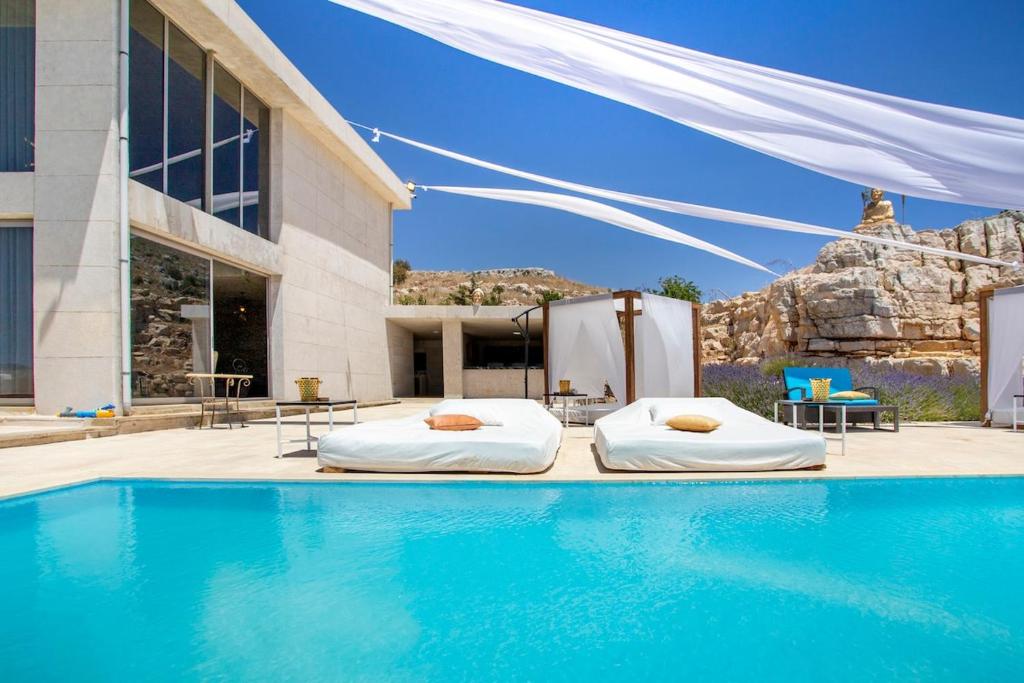 two beds in a pool next to a building at Hacienda 888 in Ḑahr al Baydar