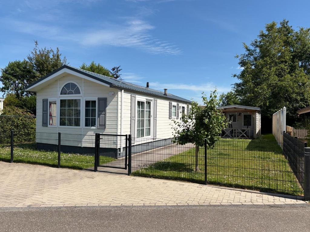 a white house with a fence in front of it at De Roos chalet 174 in Sint Annaland