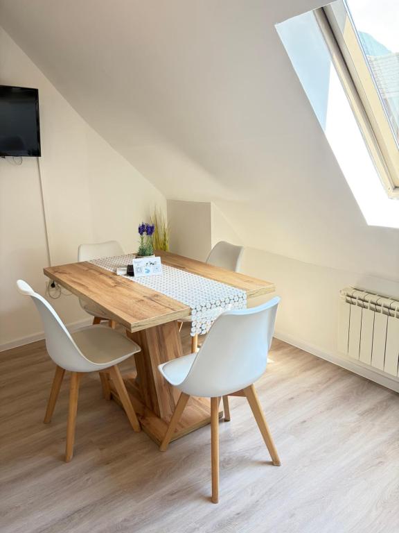 a dining room with a wooden table and two white chairs at Apartments in Green House in Bovec