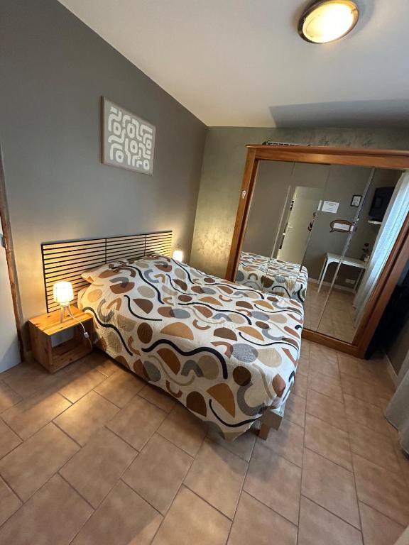a bedroom with a bed and a mirror at Studio proche RN145 Chez Greg in Saint-Sulpice-le-Guérétois