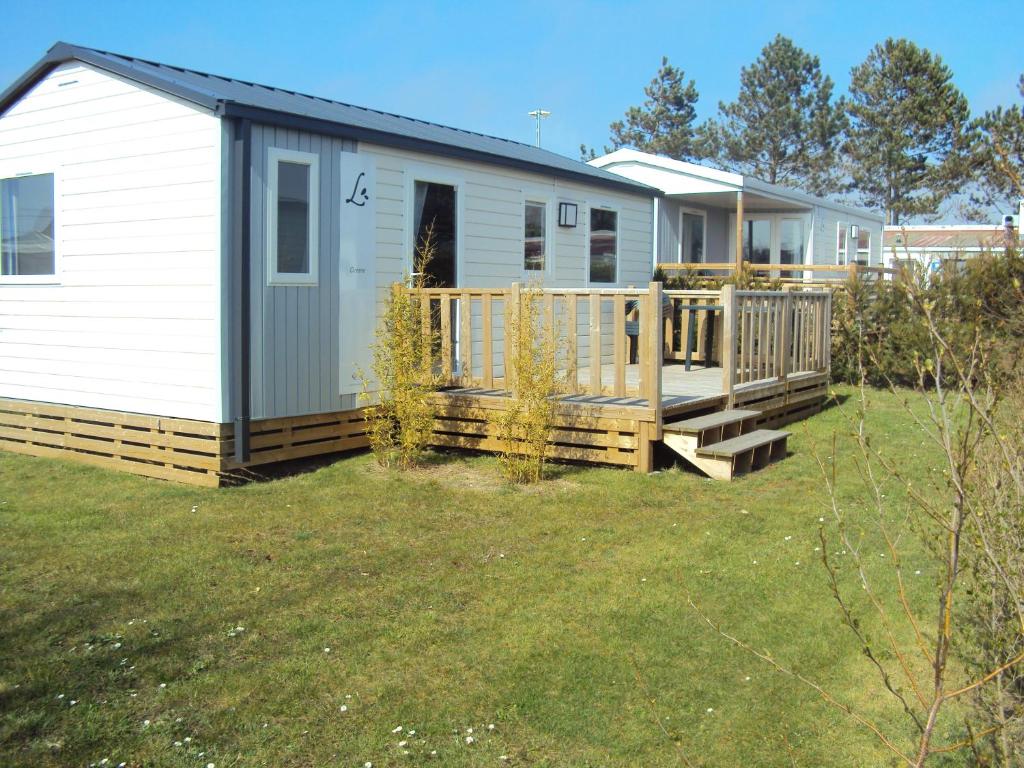 a mobile home with a porch and a deck at Camping La Forêt Stella-Plage in Stella-Plage