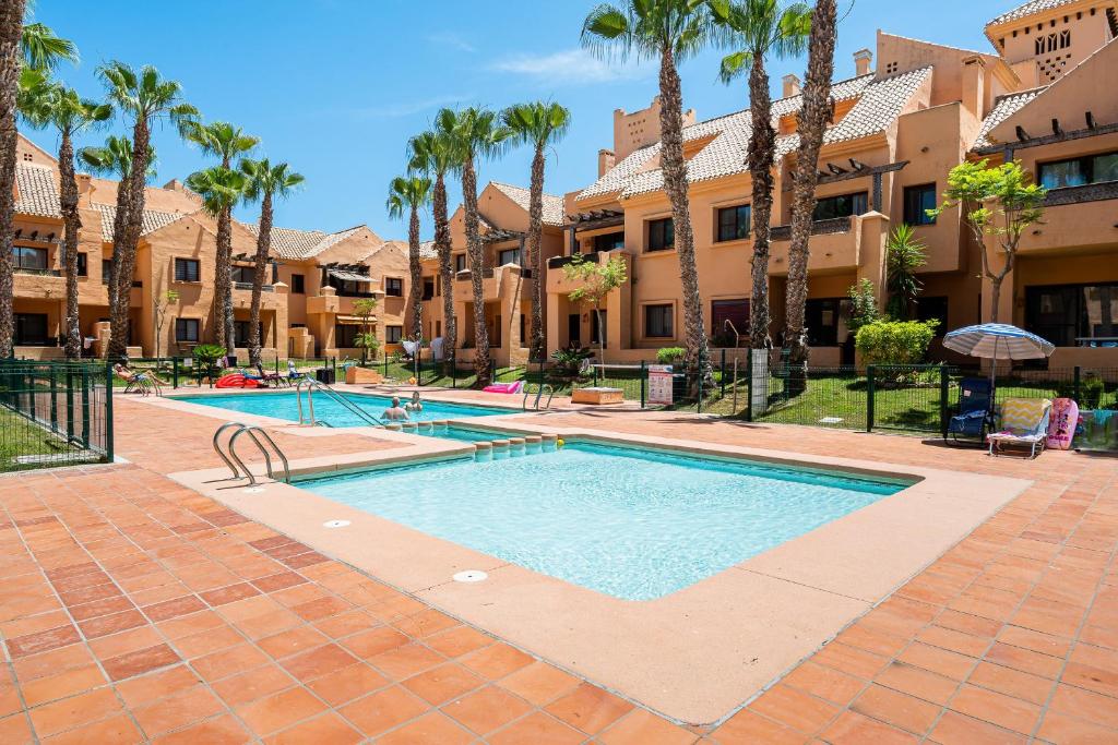 a swimming pool at a resort with palm trees at Ribera Beach in Los Alcázares