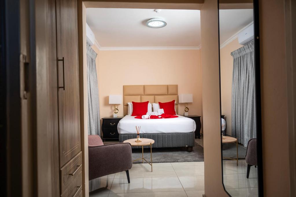 a bedroom with a bed with red pillows and a chair at Sycamon Suites in Jwaneng