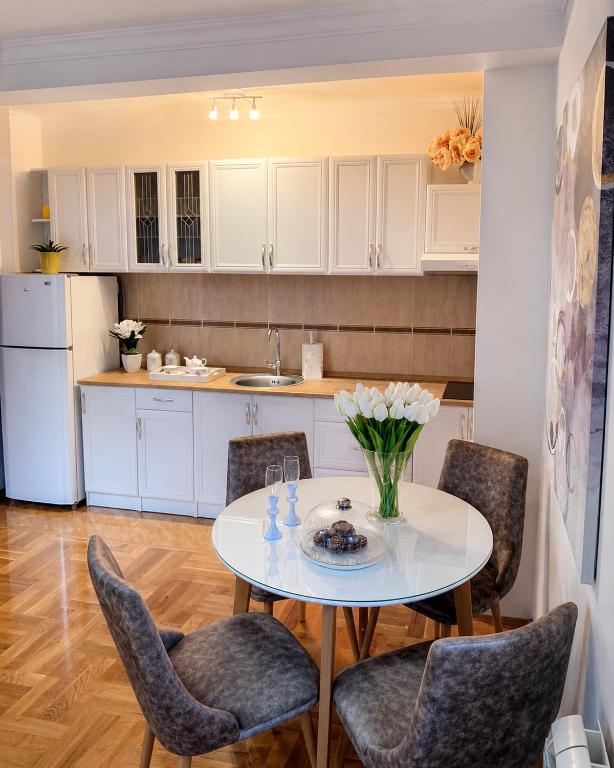 a kitchen with a table with chairs and a white refrigerator at Prizma in Cetinje
