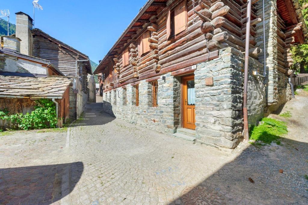 a stone building with a wooden door on a street at Lueur de la Rouja in Champoluc