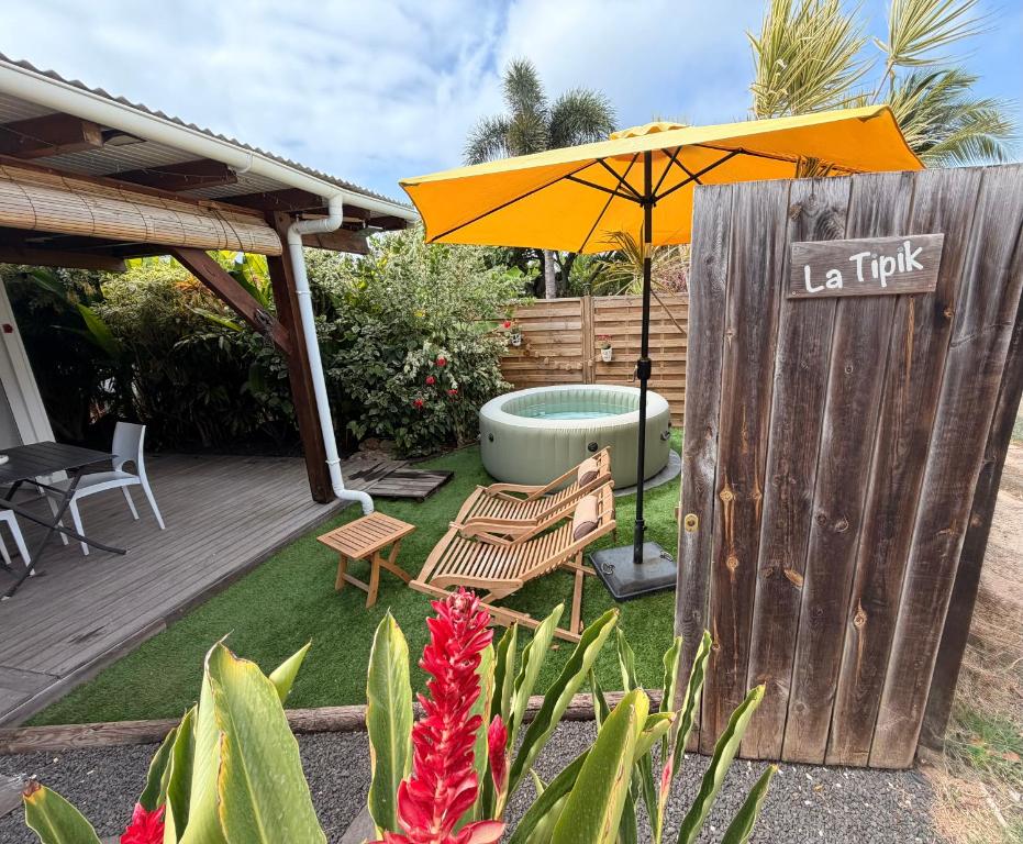 a backyard with a hot tub and an umbrella at Bungalow la tipik in Saint-François
