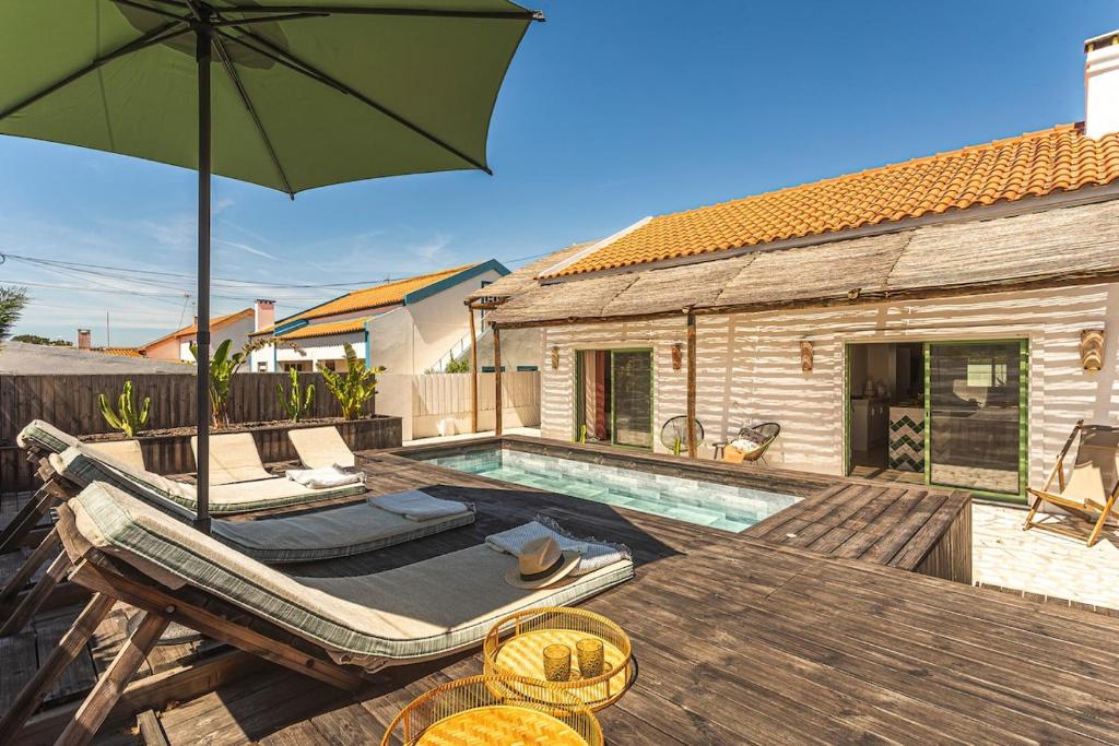 a patio with a pool and a table with an umbrella at Villa Arta by Hostiva in Comporta