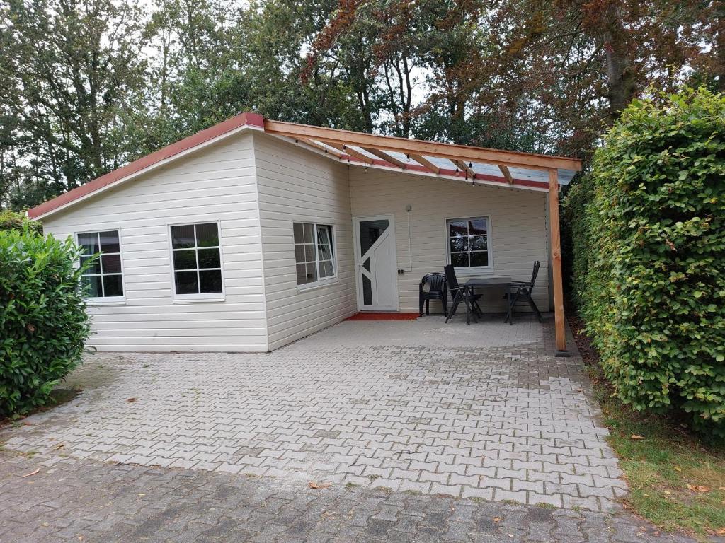 a small white house with a table in it at Boslodge 7 personen in Tiendeveen