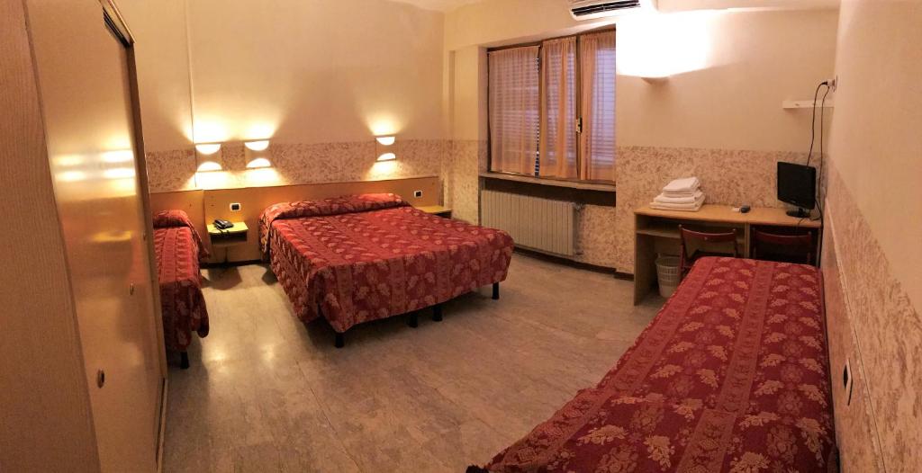 una camera d'albergo con due letti e una scrivania di Hotel Nettuno a Milano