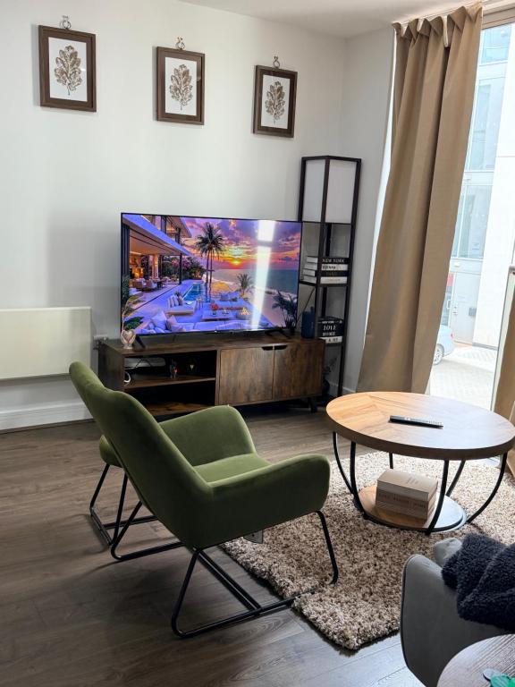 a living room with a tv and a green chair and a table at Cozy One bedroom with Free Underground parking in Mailbox Birmingham city in Birmingham