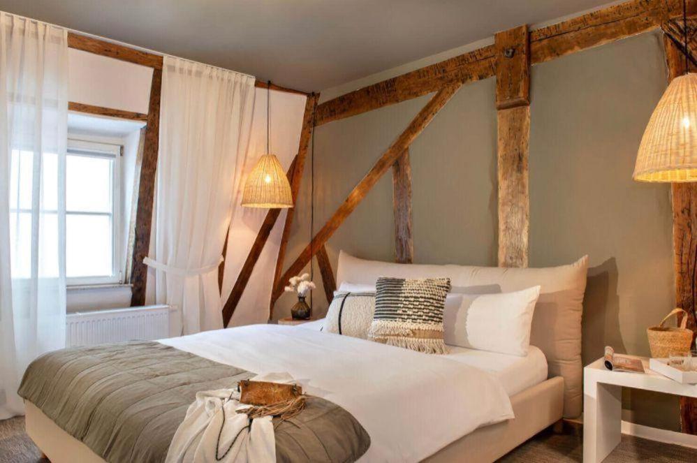 a bedroom with a large white bed with wooden beams at Hotel Fuchs in Saarbrücken