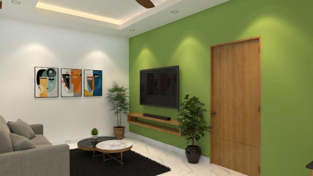 a living room with a couch and a television on a wall at SUITE ROOMS Sarjapur Road Near to HSR Layout in Bangalore