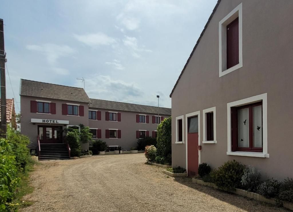 a building with a dirt road in front of it at Logis Hôtel Le Merle Blanc in Digoin