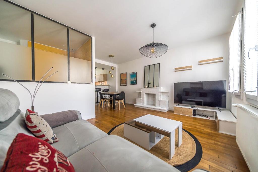 a living room with a couch and a tv at Le Balcon Gaillard in Brive-la-Gaillarde