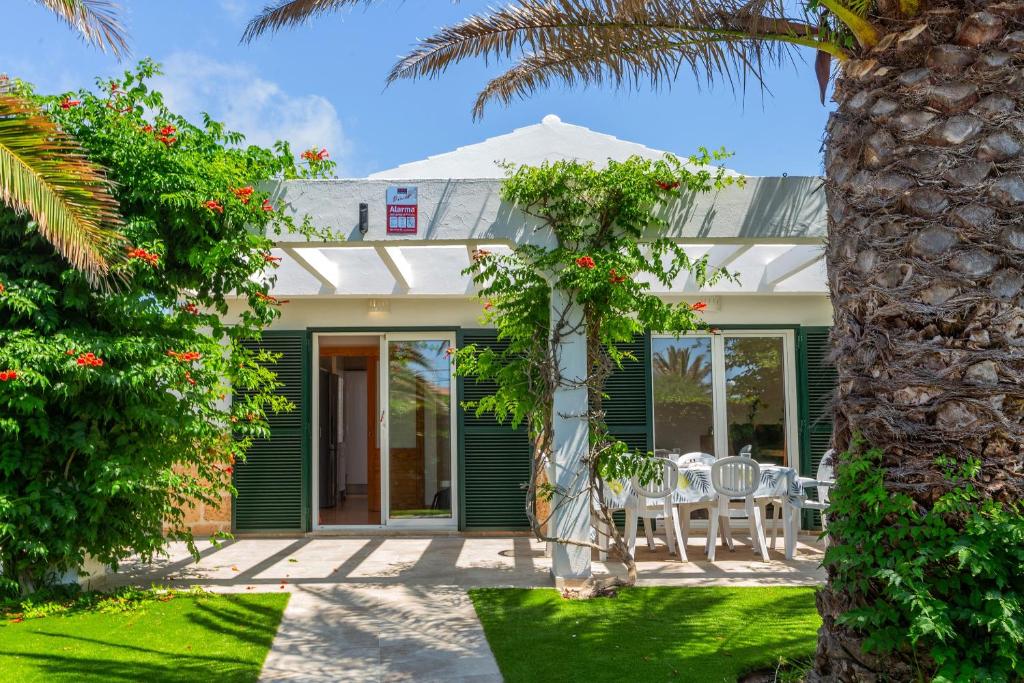a house with a patio with chairs and a palm tree at Villa Jaume in Cala en Bosc