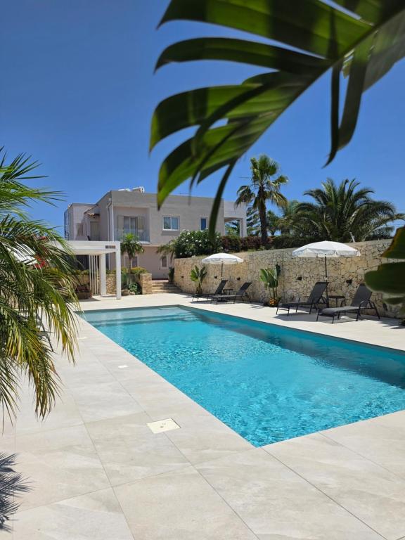 a pool with chairs and umbrellas next to a building at Villa Merilusi Apartments in Fontane Bianche