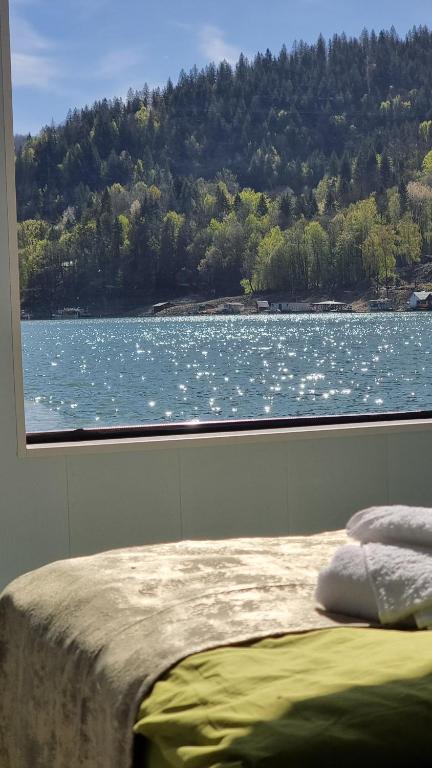 a bedroom with a view of a lake from a window at Baraj Izvorul Muntelui Bibanu in Bicaz