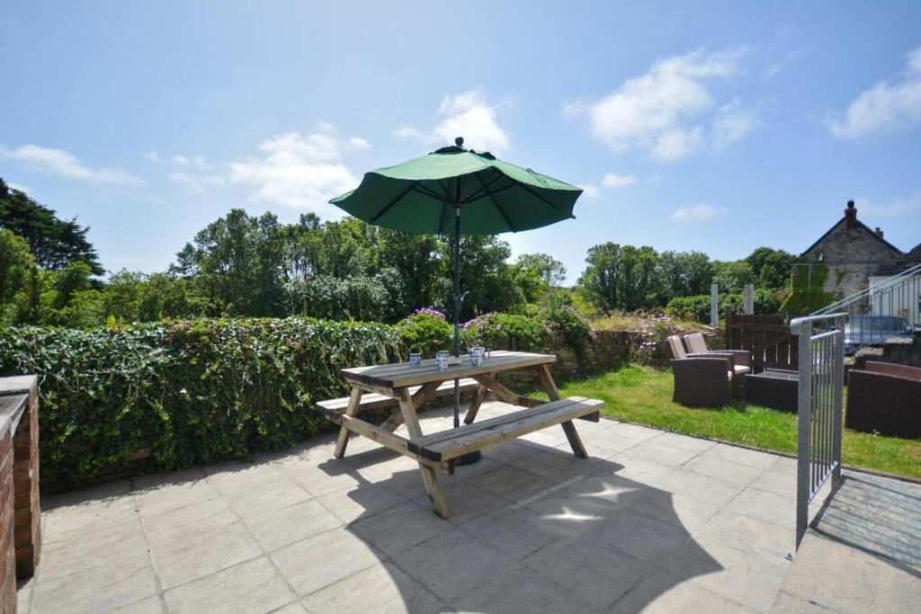 a picnic table with an umbrella on a patio at 3 Bed in Padstow oc-treba in Saint Merryn