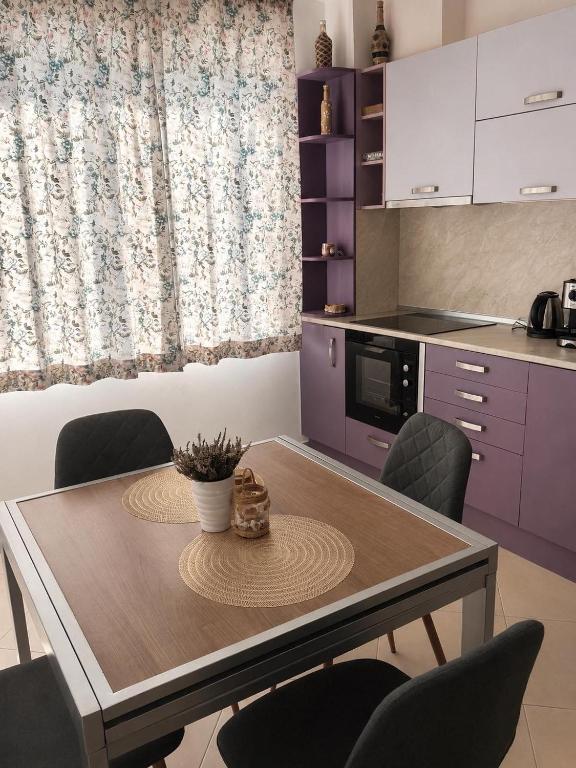 a kitchen with a wooden table and purple cabinets at Cherno More Apartment in Ahtopol
