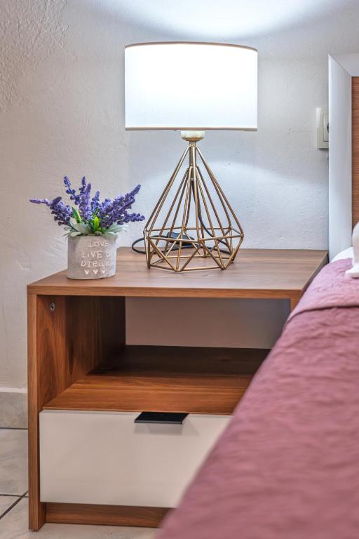a bedside table with a lamp and flowers on it at 4 seasons home Ofrinio in Ofrínion