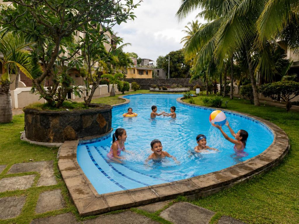 a group of children playing in a pool with a beach ball at ARIEL BEACH VILLA* in Grand-Baie