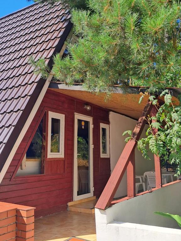 a house with a red roof with a patio at Domki Wakacyjne nad Jeziorem in Janowice
