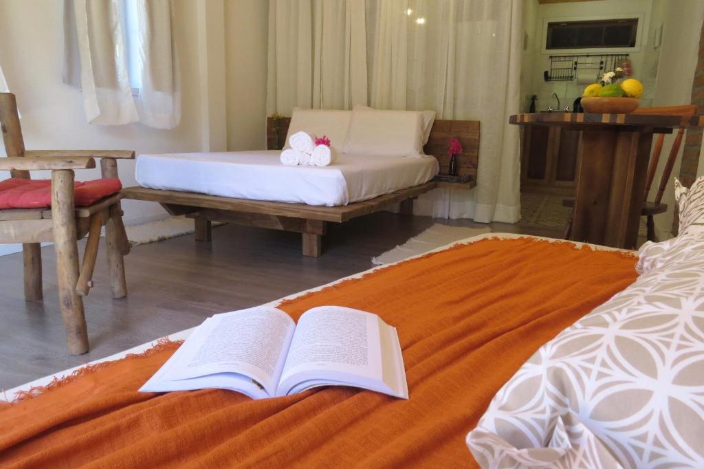 a bedroom with a bed with an open book on it at Pousada Pedras Rollantes - Estúdios Enxaimel in Barracão