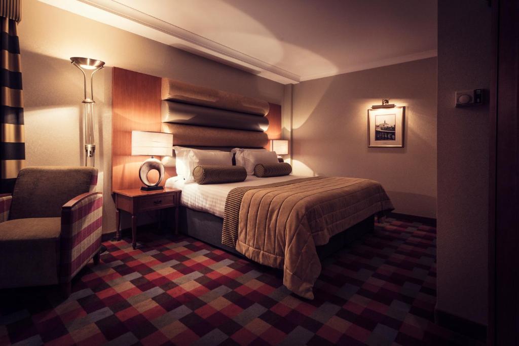 a hotel room with a bed and a chair at Carlton George Hotel in Glasgow