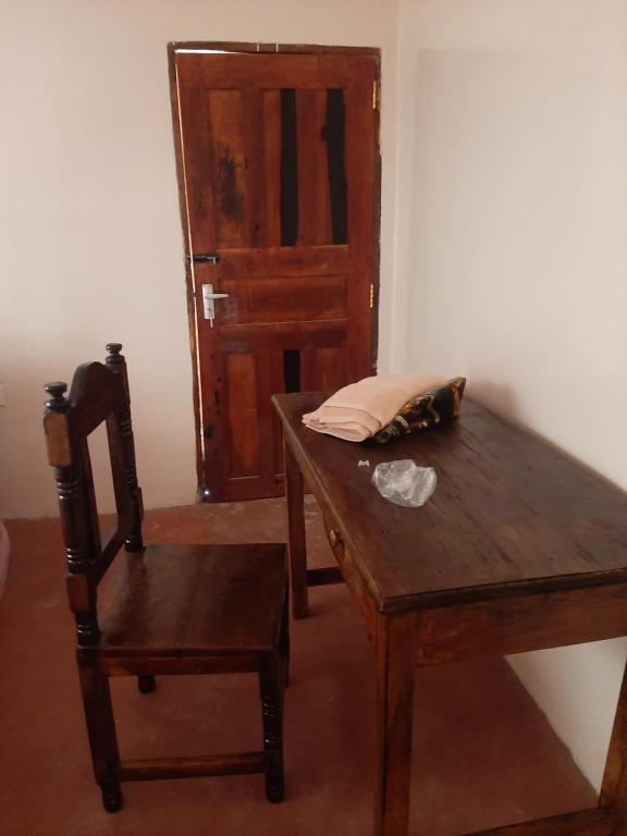 a wooden table and a chair in a room with a door at Royal guest home in Mokowe