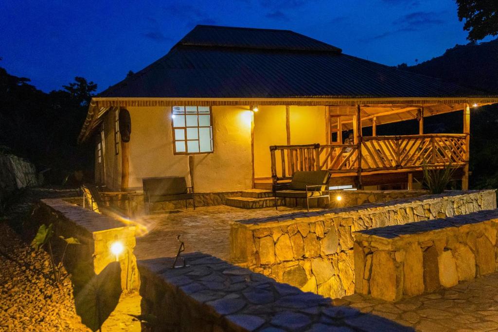 a house with a stone wall in front of it at night at Riverside Gorilla Lodge - Bwindi in Kinkizi