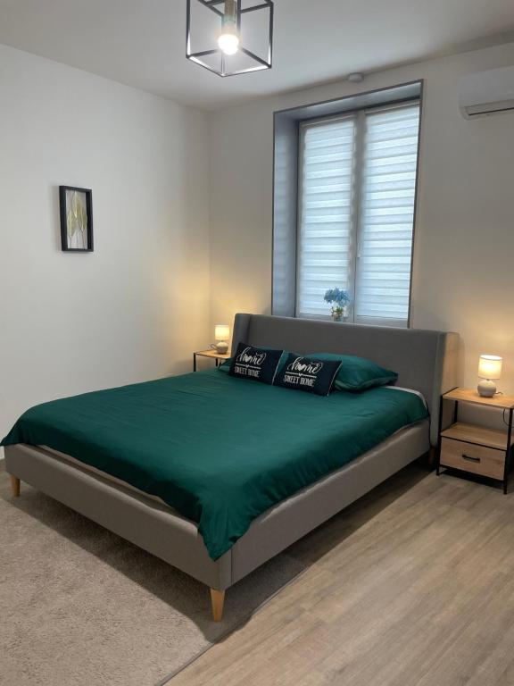 a bedroom with a bed with green sheets and a window at Appartement Dio in Dinant