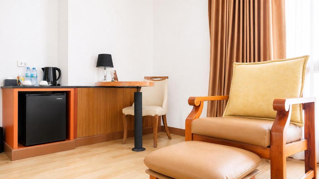 A compact hotel work and refreshment corner with an armchair and footstool.