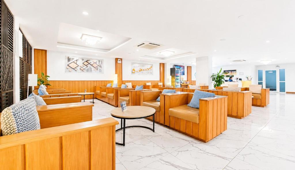 A bright lounge with wooden armchairs, sofas, tables and marble-look flooring.